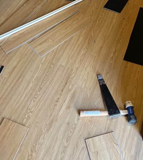 Plank flooring installation in progress with tools on the floor